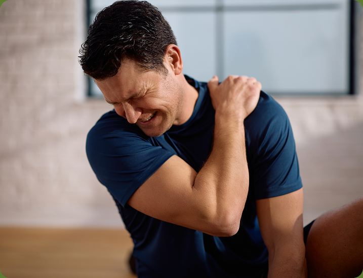 Man wincing and holding a painful shoulder