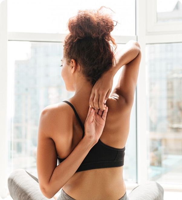 Woman doing a shoulder stretch by a window