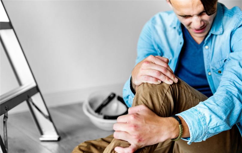 Man sitting on the floor holding his knee after a fall