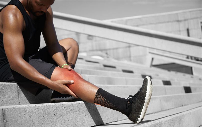 Athlete holding a strained calf muscle on stadium steps